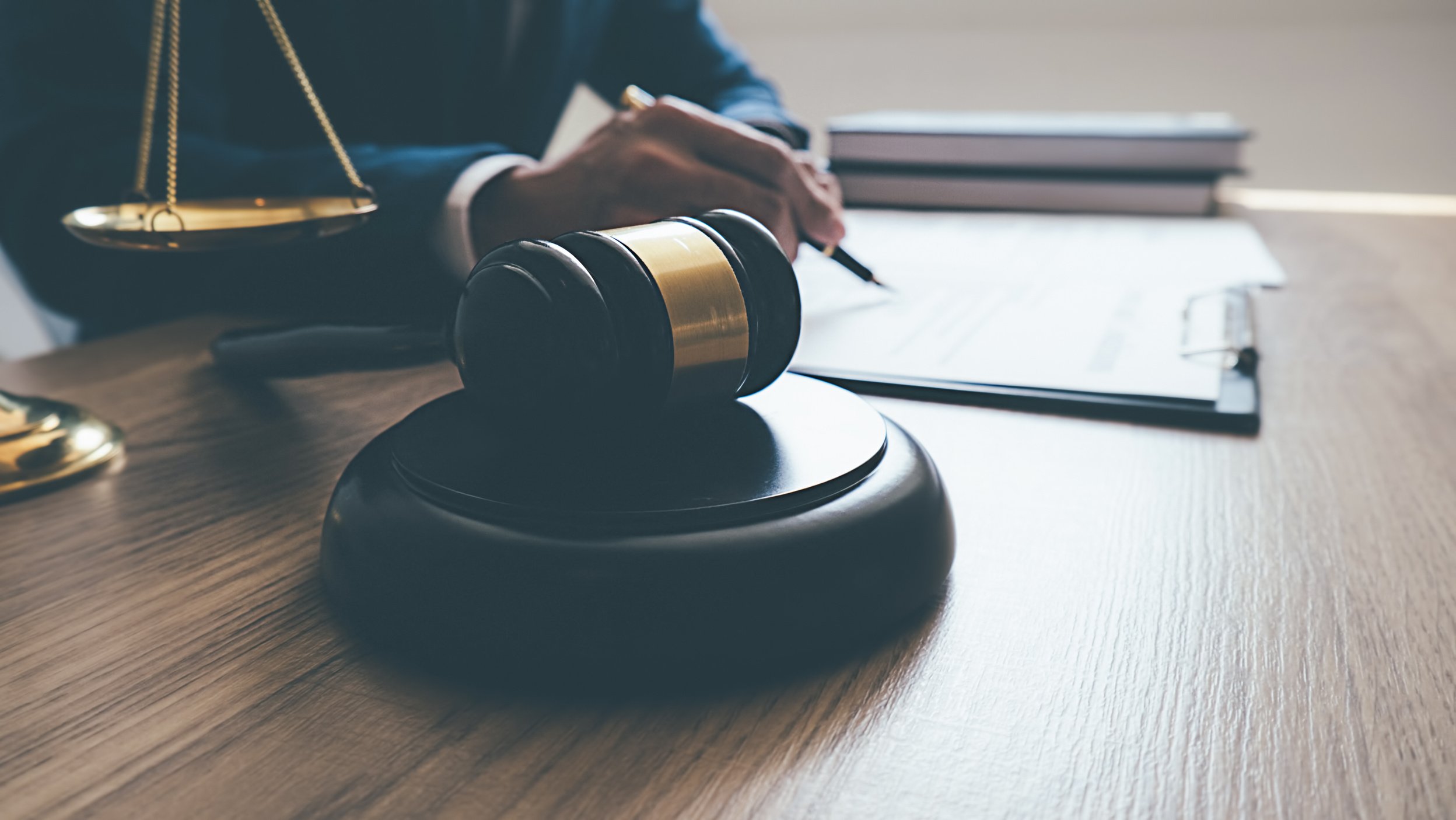 Hands Writing with Gavel with Balance Scale at the Table